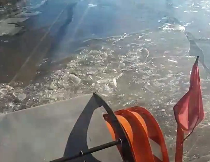 Folyami jégtörőként megy a Közút hókotrója a vízzel elárasztott utakon – videó