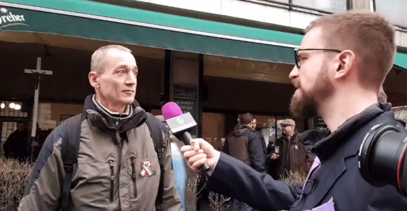 Gulyás Márton kerítésszaggató pálinkával kínálja a CÖF-menet tüntetőit