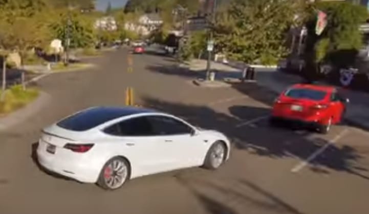 Szép drónos felvétel egy önvezető Tesláról, amint majdnem nekimegy egy parkoló kocsinak