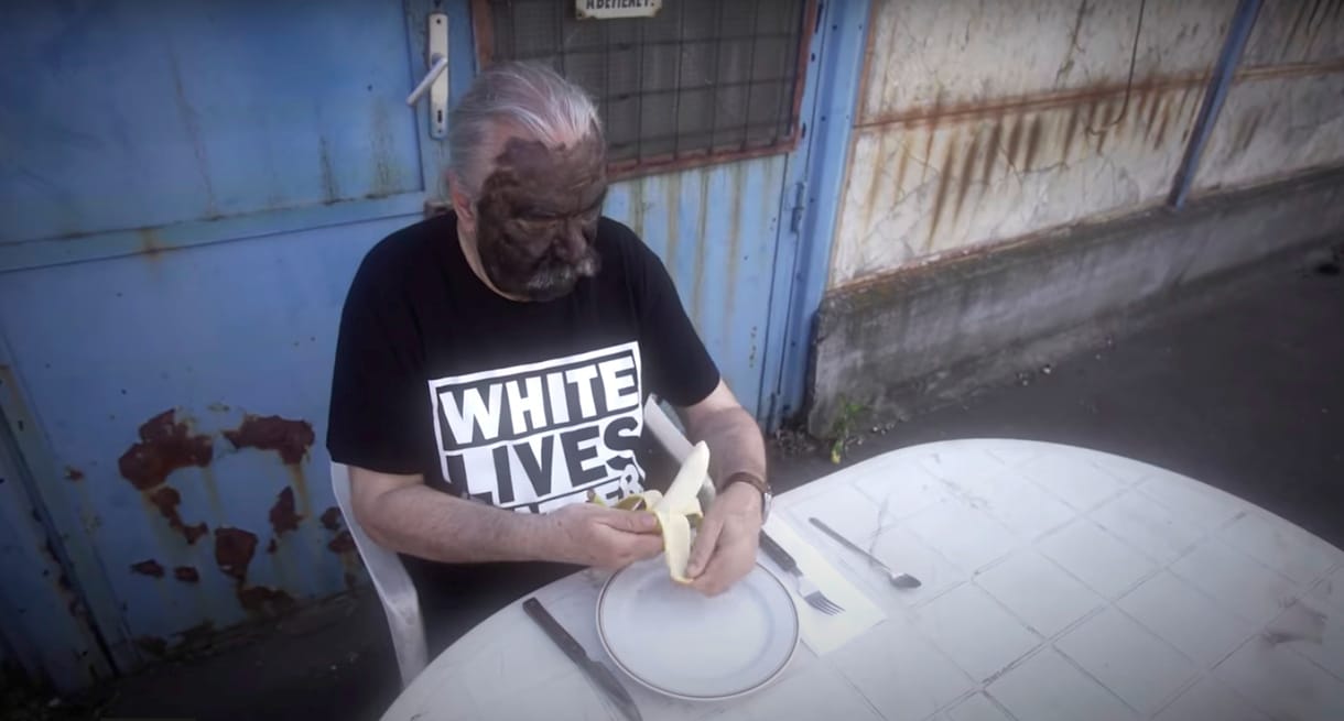 Schuster Lóránt blackface-ben, White Lives Matter pólóban hámozza a banánt