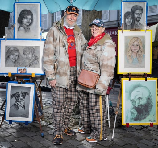 Michel és Claudine művész karikaturisták, akik turisták portréit rajzolják, pózolnak a párizsi Place du Tertre-en 2024. április 10-én.