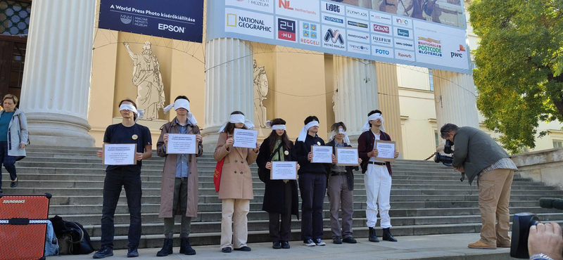 Bekötött szemmel tiltakoztak a Nemzeti Múzeum előtt a korhatáros sajtófotó-kiállítás ellen